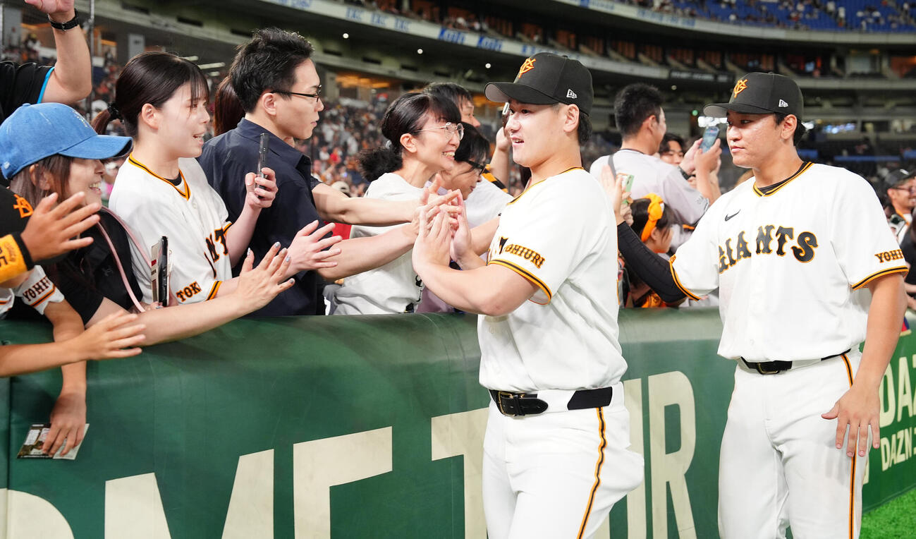 巨人対広島　ファンとハイタッチするる巨人井上温大と笹原操希（右）（撮影・鈴木みどり）