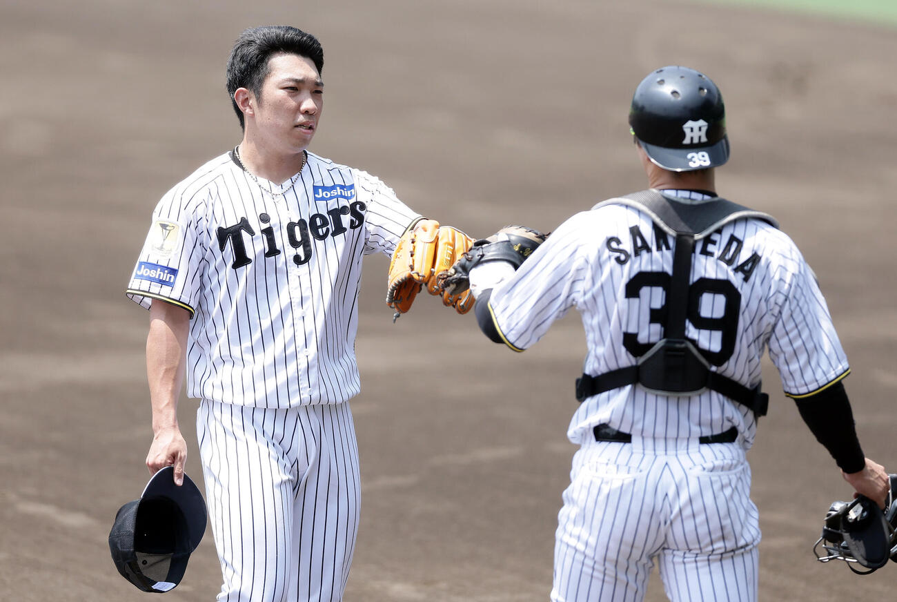 ライブBPでの登板を終え栄枝裕貴（右）とタッチを交わす阪神石井大智（撮影・前田充）
