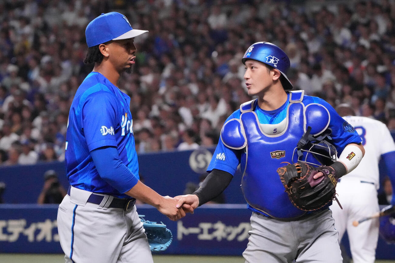 中日対DeNA 1回終了、松尾汐恩（右）と握手を交わしベンチへ戻るDeNA先発のオスバルド・ビド（撮影・森本幸一）
