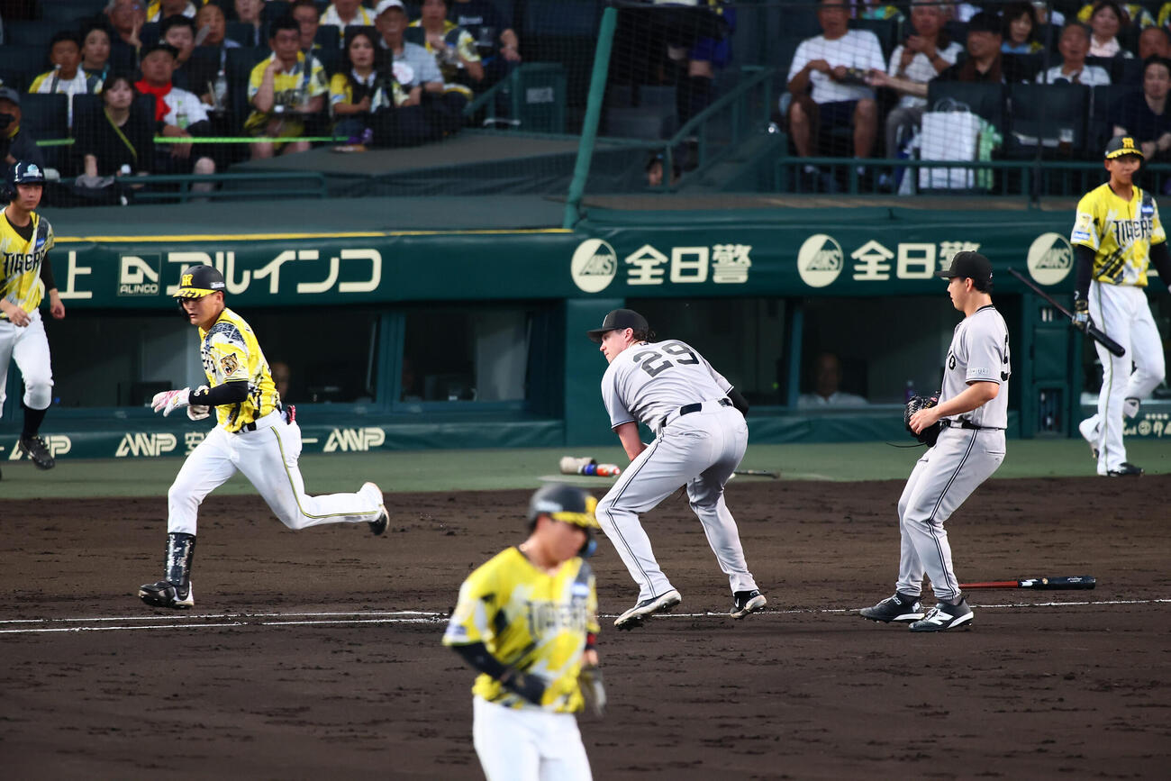 阪神対巨人　4回裏阪神無死一塁、元山飛優は一塁線にバントを決める。右は一塁手ボビー・ダルベック、右端は小笠原慎之介（撮影・加藤哉）