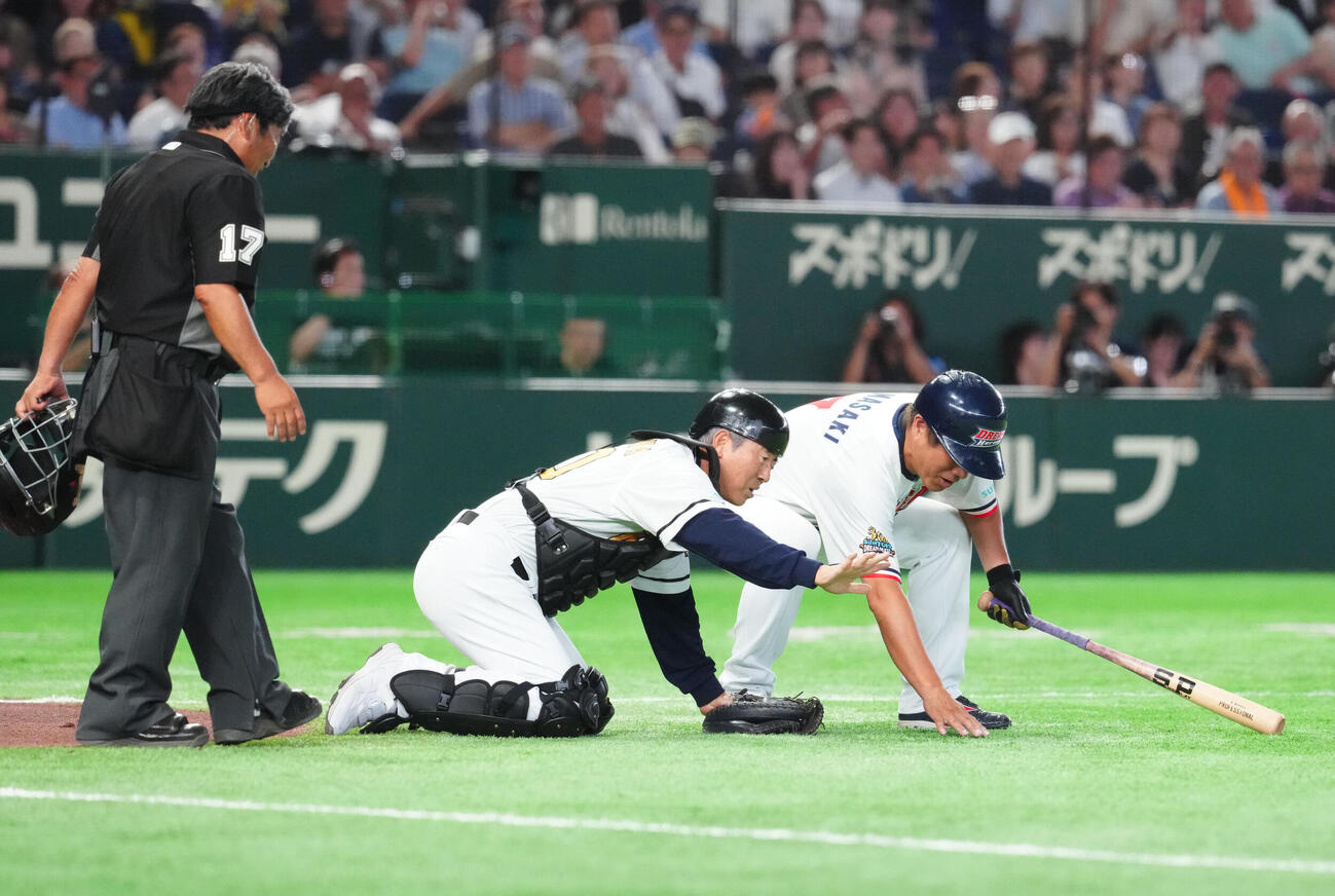 ザ・プレミアム・モルツ球団対ドリーム・ヒーローズ　4回表、コンタクトを落としたとアピールし探すザ・プレミアム・モルツ球団捕手の達川光男氏（中央）（撮影・江口和貴）