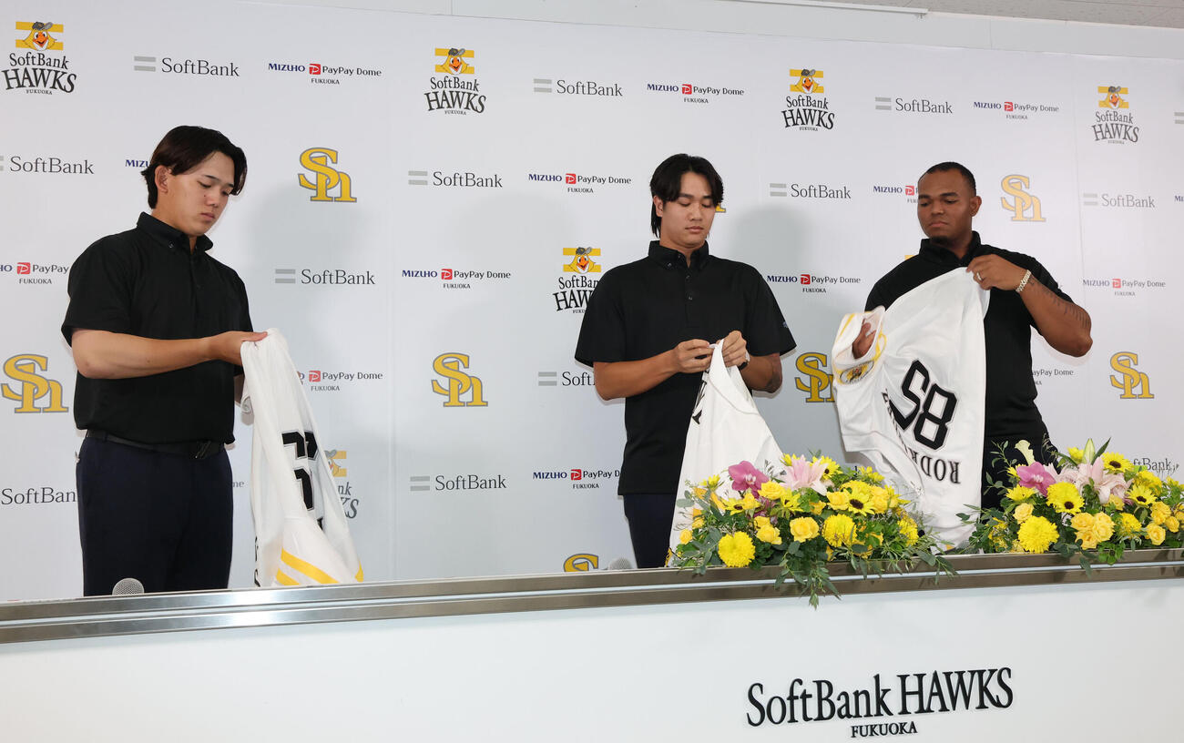 ソフトバンクに支配下登録された左から小林樹斗、張峻瑋、ルイス・ロドリゲスはユニホームに袖を通す（撮影・梅根麻紀）