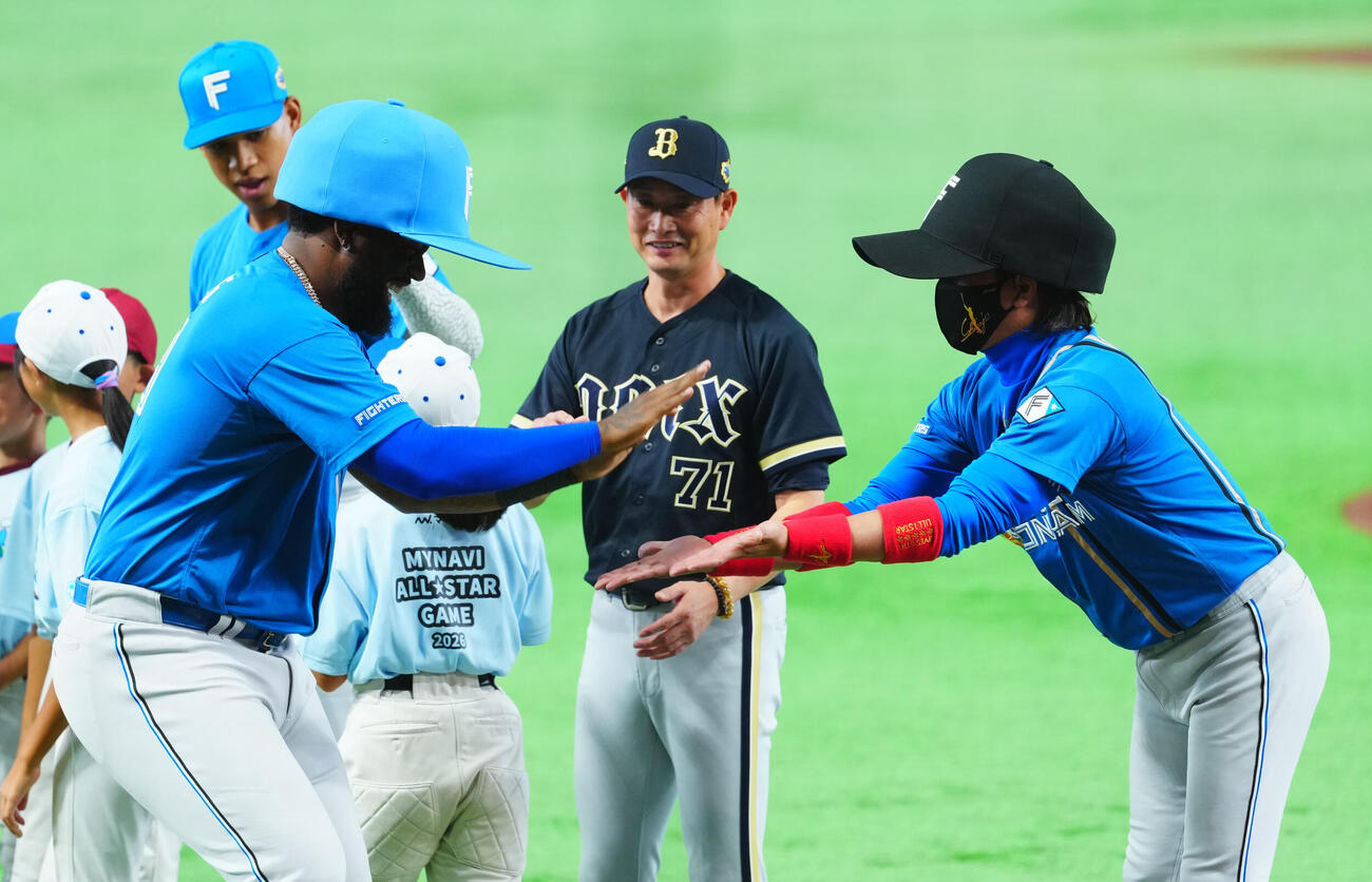全セ対全パ　選手紹介で大きな帽子をかぶりタッチを交わす全パフランミル・レイエス（左）と新庄剛志コーチ（撮影・垰建太）