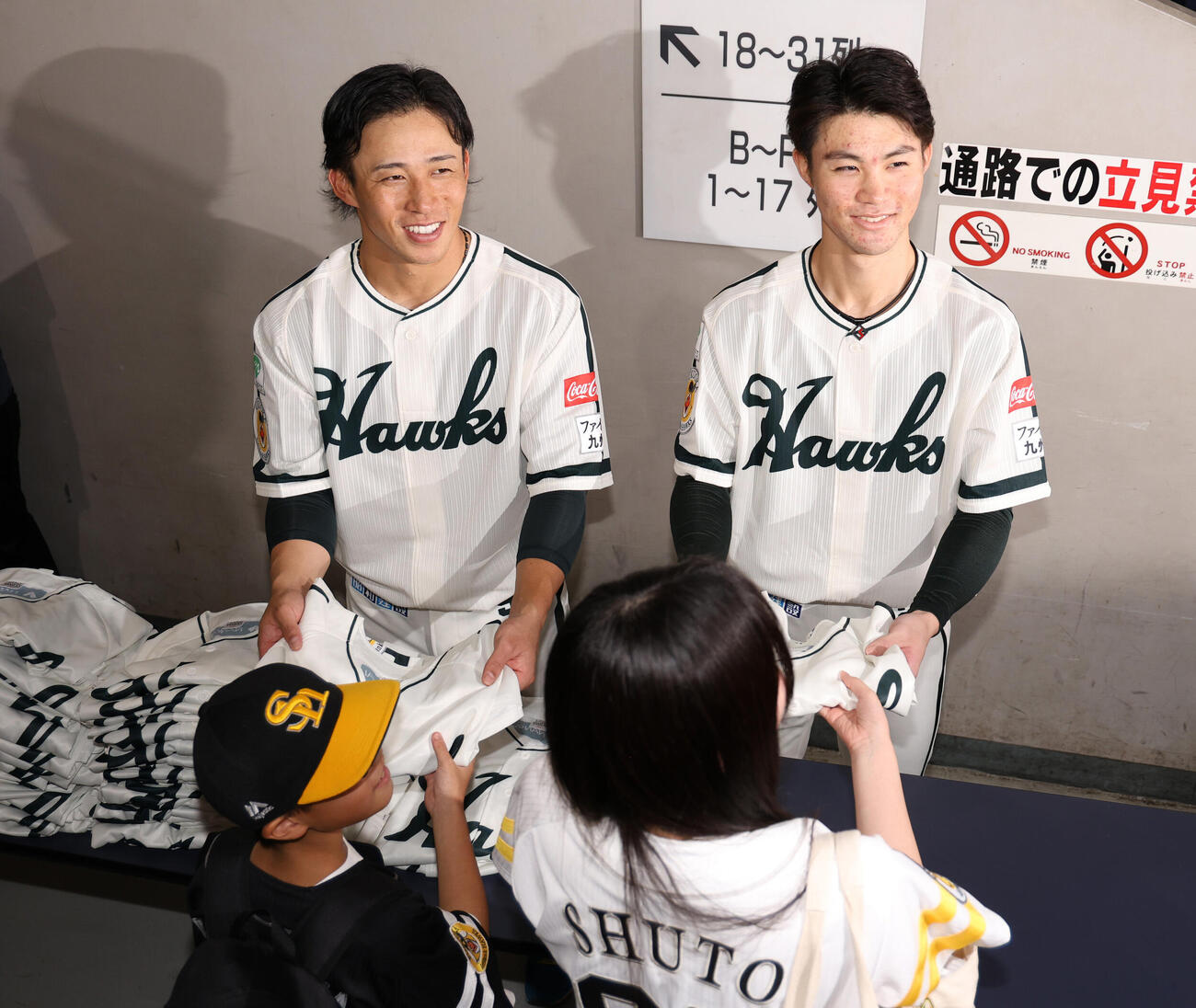 ソフトバンク対日本ハム　南海ホークス復刻ナイターin大阪と銘打って行われ、ファンに復刻ユニホームを配る野村勇（左）と庄子雄大（撮影・西尾就之）