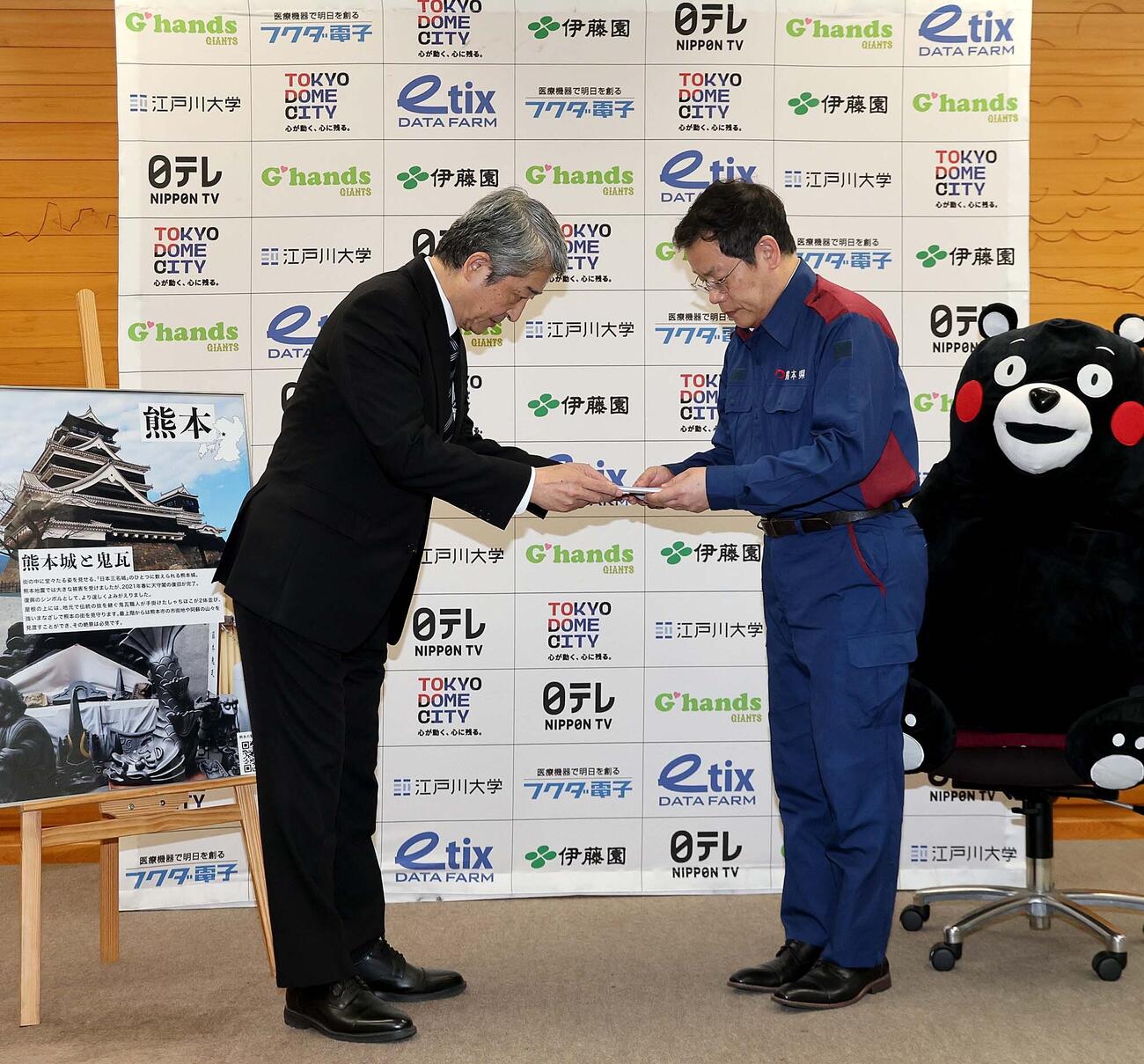 巨人の国松徹球団社長（左)が熊本県東京事務所の田口雄一所長（右)に計2000万円を寄付