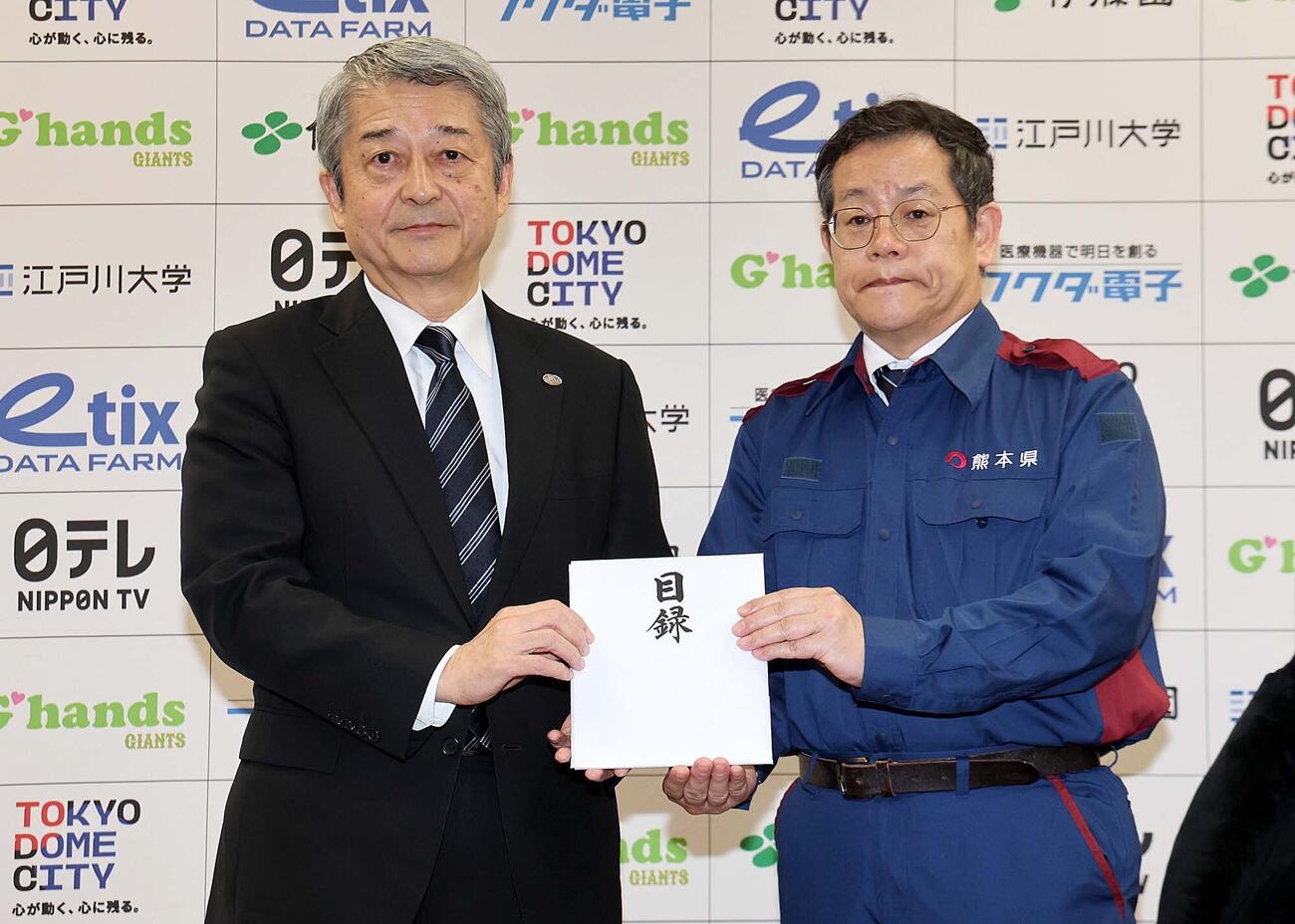 巨人の国松徹球団社長（左)が熊本県東京事務所の田口雄一所長（右)に計2000万円を寄付