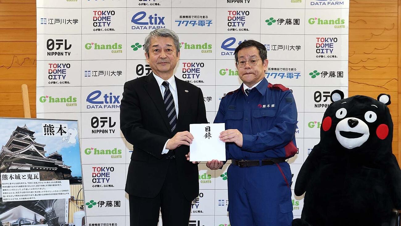 巨人の国松徹球団社長（左)が熊本県東京事務所の田口雄一所長（右)に計2000万円を寄付