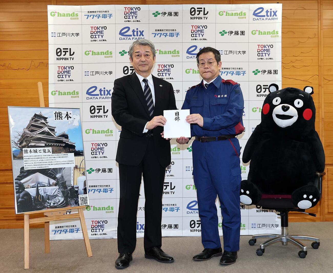 巨人の国松徹球団社長（左)が熊本県東京事務所の田口雄一所長（右)に計2000万円を寄付