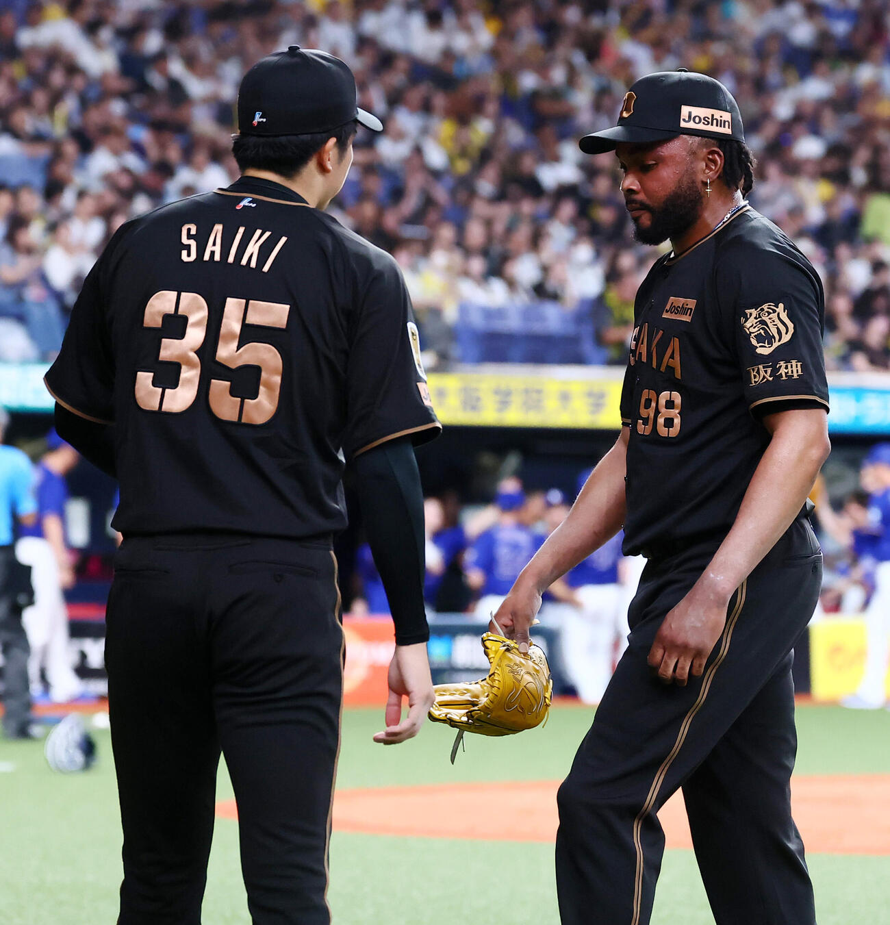 阪神対中日　9回表に登板し中日に逆転を許した阪神ラファエル・ドリスは才木浩人（左）の出迎えを受ける（撮影・加藤哉）
