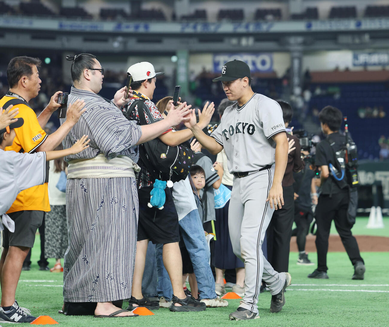 巨人対ヤクルト　場内一周しお相撲さんとタッチを交わす笹原操希（撮影・増田悦実）