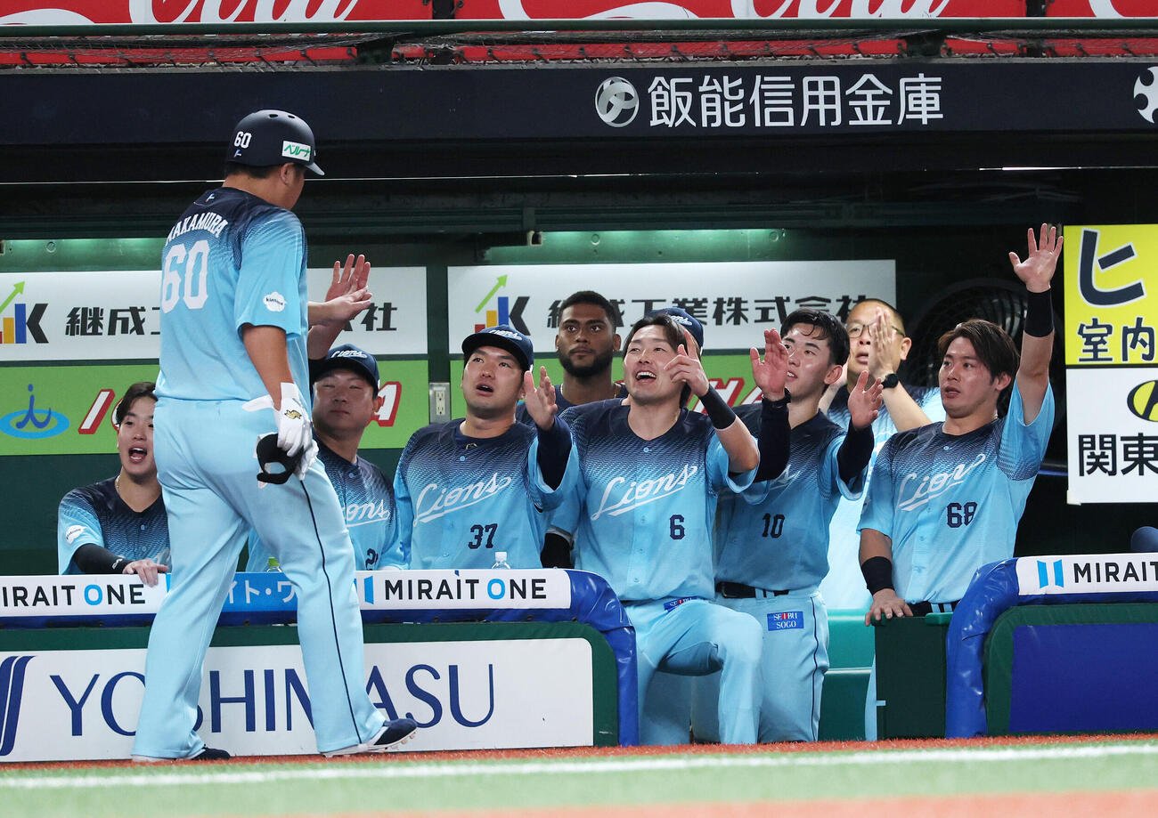 西武対ソフトバンク　7回裏西武1死、中村剛也（左）は左前打を放ち選手たちに迎えられる（撮影・鈴木正人）