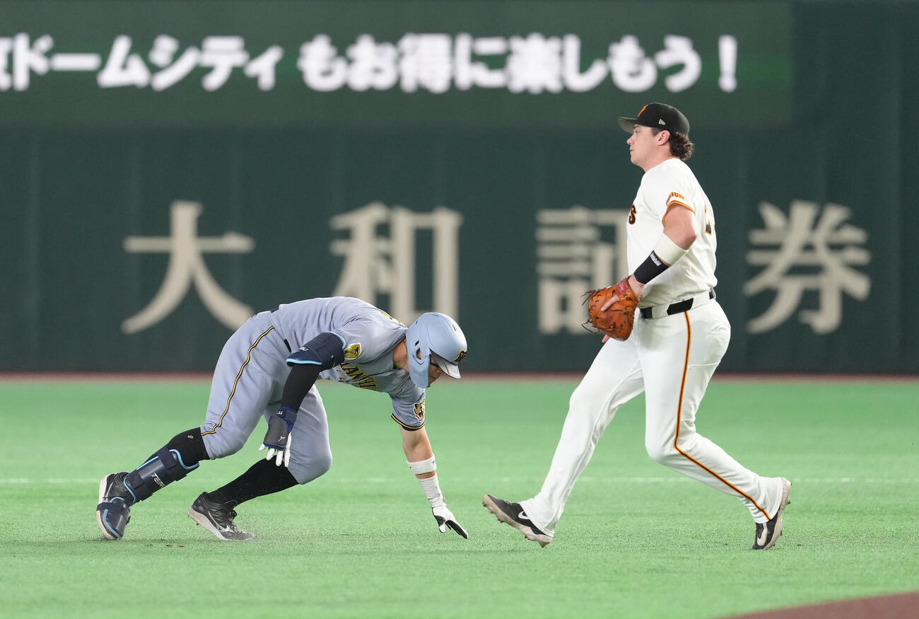 巨人対阪神　1回表阪神1死、1死二塁、佐藤輝明（左）は先制適時打で二塁を狙うも挟まれる（撮影・足立雅史）