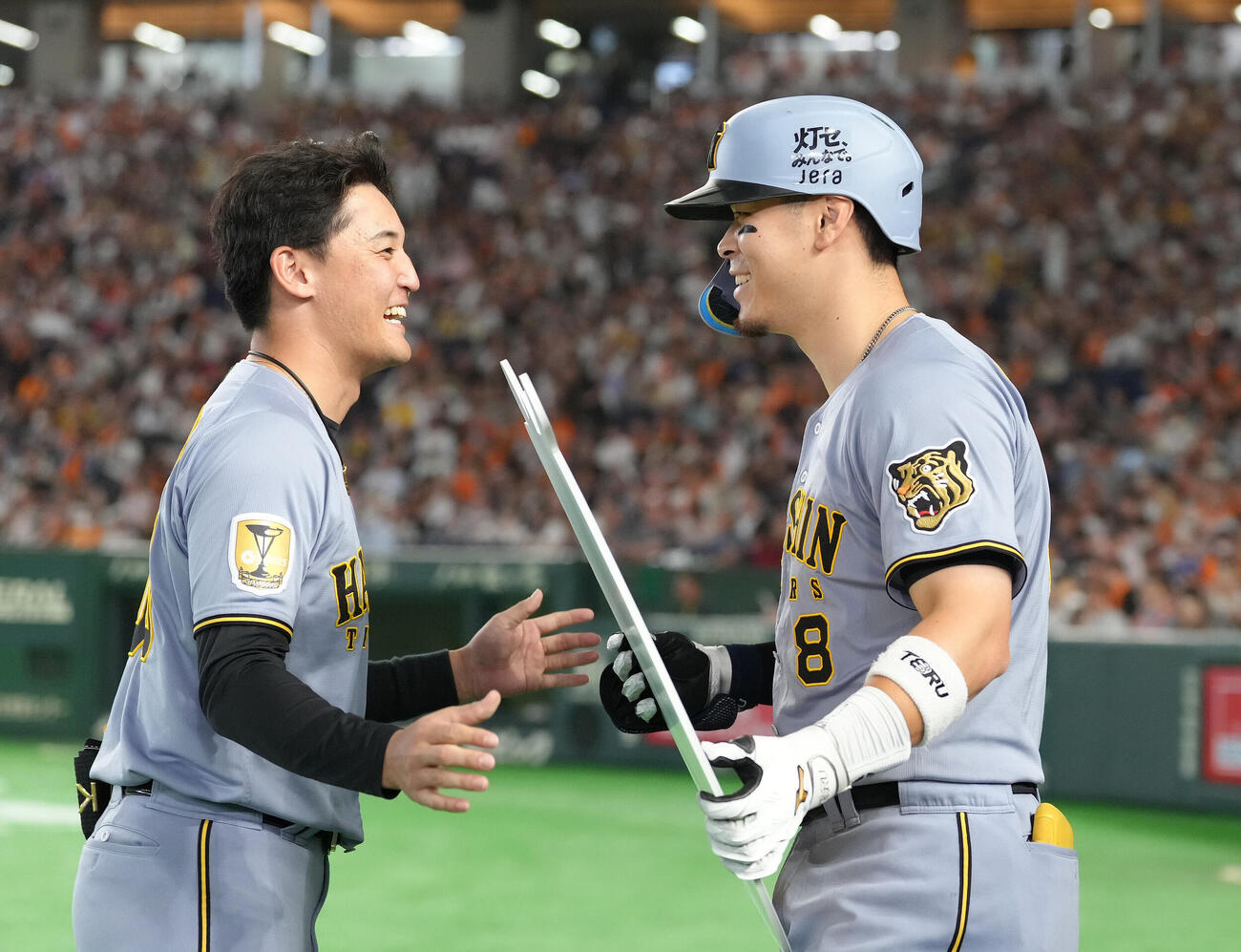7回表阪神無死、佐藤輝明（右）は通算150号本塁打を放ち元山飛優から記念ボードを受け取り笑顔