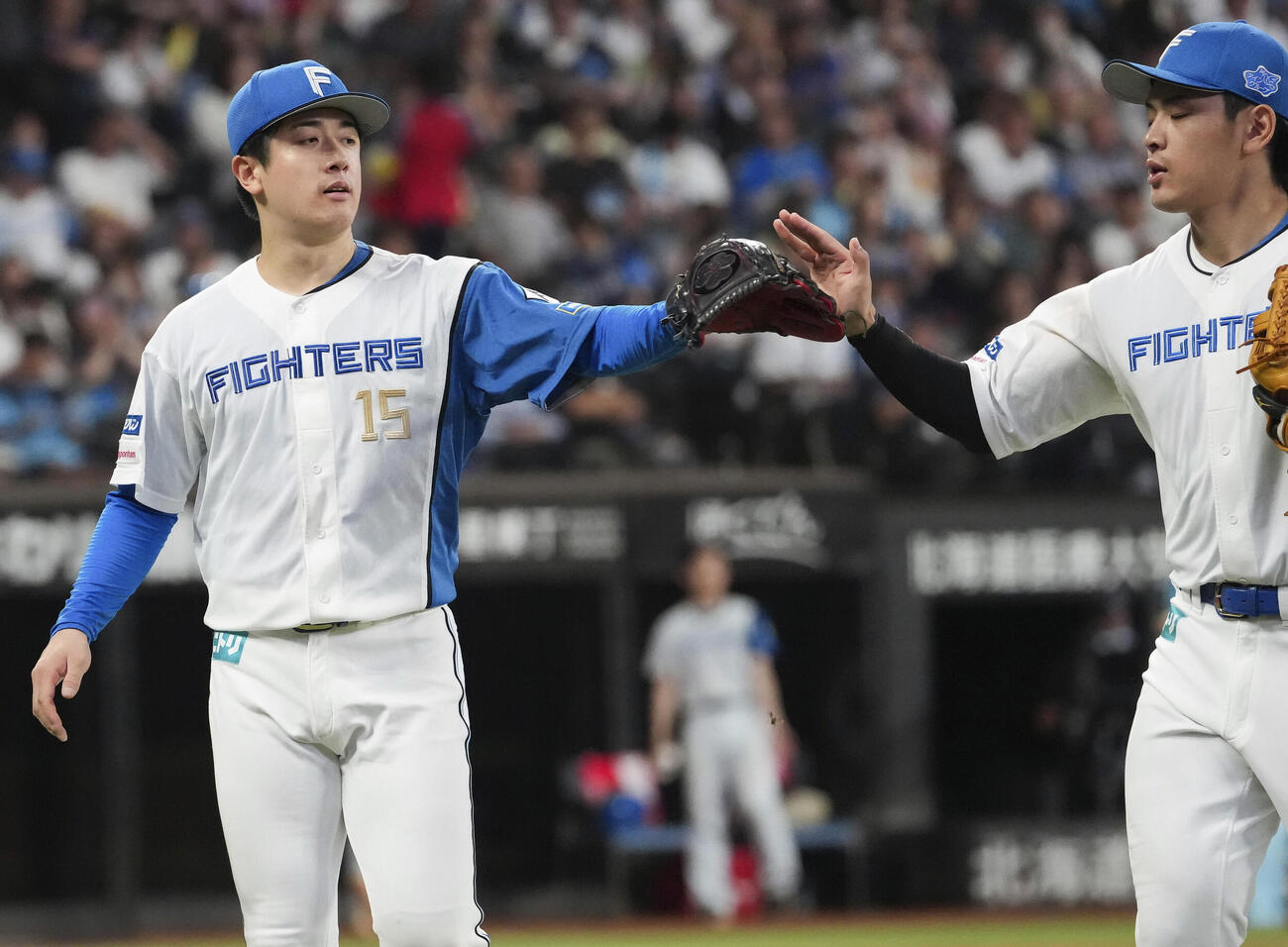 6回を投げ終え、三塁手野村（右）とタッチを交わす日本ハム北山（共同）