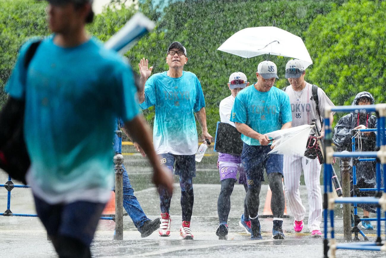 ヤクルト対広島　試合前、雨の中、室内練習場から移動するヤクルト池山隆寛監督（後方左）ら（撮影・江口和貴）