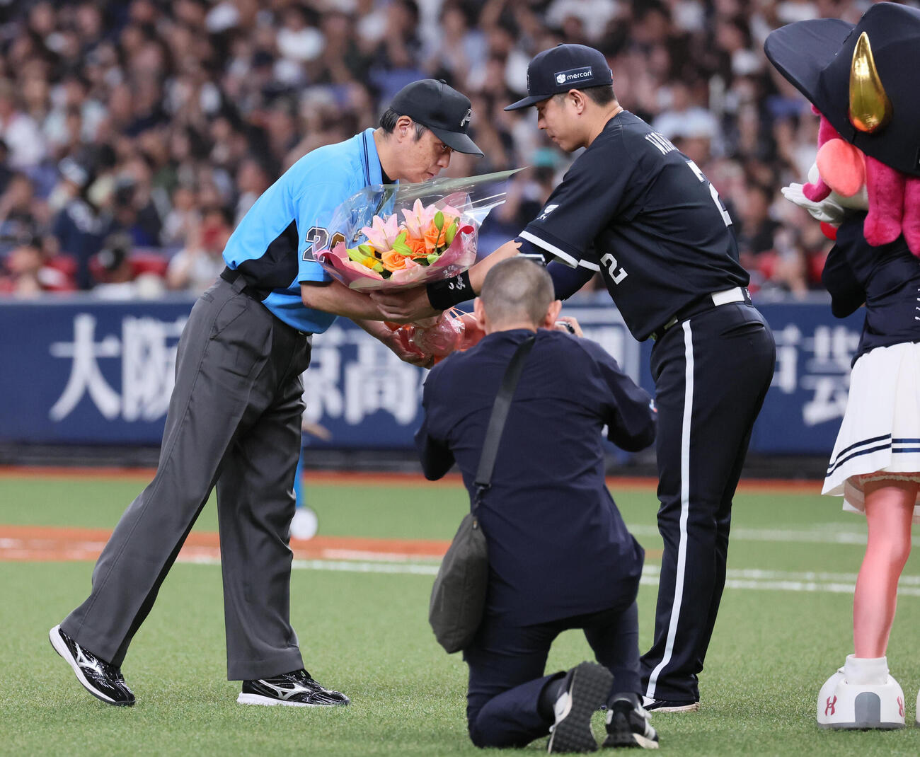 オリックス対日本ハム　2000試合出場を達成した白井一行審判員は若月健矢（右）から花束を受け取る（撮影・宮崎幸一）