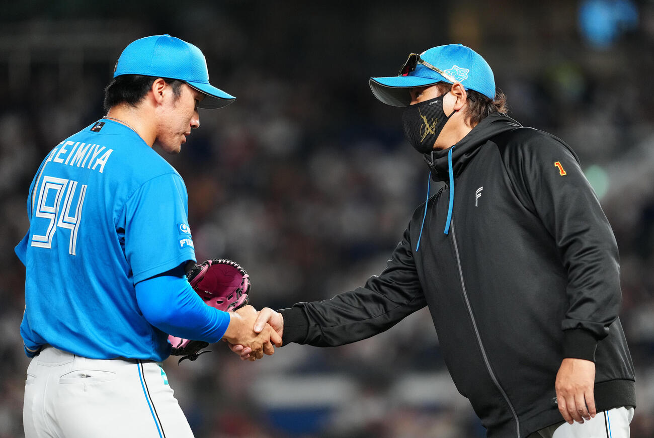 ロッテ対日本ハム　10回裏のマウンドに向かう清宮虎多朗（左）を握手で送り出す日本ハム新庄剛志監督（撮影・鈴木みどり）