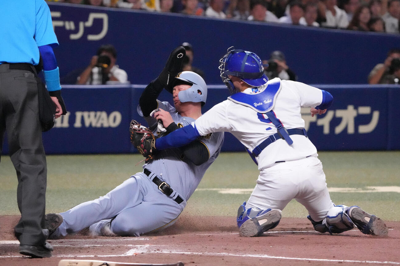 中日対阪神　4回表阪神無死一、二塁、大山悠輔の安打で本塁突入するもタッチアウトの森下翔太（中央）捕手は石伊雄太（撮影・森本幸一）