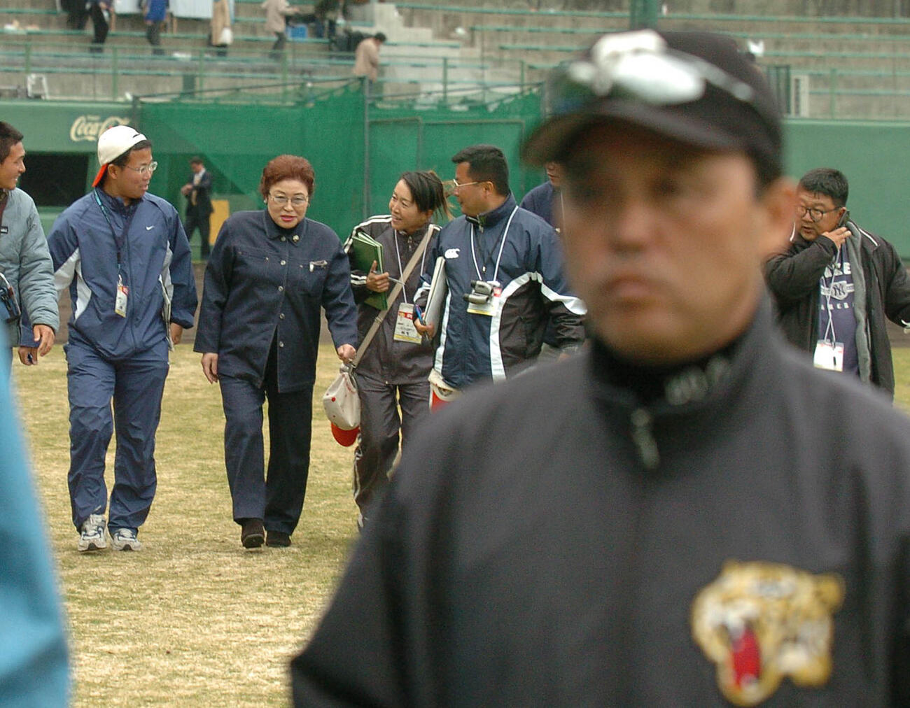 2004年2月　オープン戦　阪神対オリックス　試合後、息子の阪神・岡田彰布監督（右）の後方を歩いて引き上げる母の岡田サカヨさん