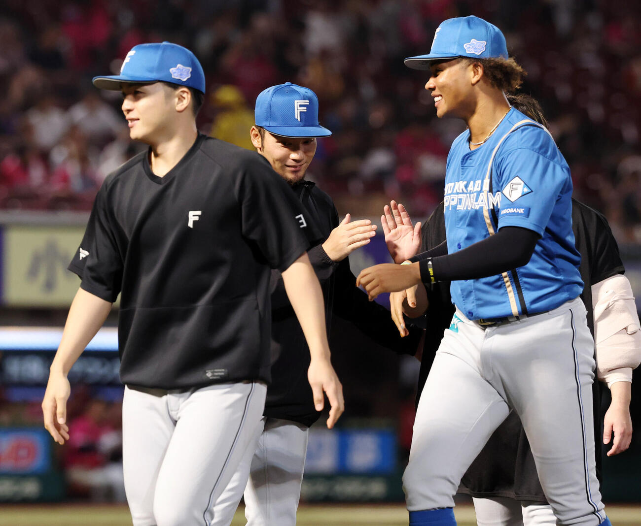 楽天対日本ハム　9勝目を挙げた日本ハム伊藤大海（左）は郡司裕也（手前左）らから祝福され、笑みを浮かべる（撮影・浅見桂子）