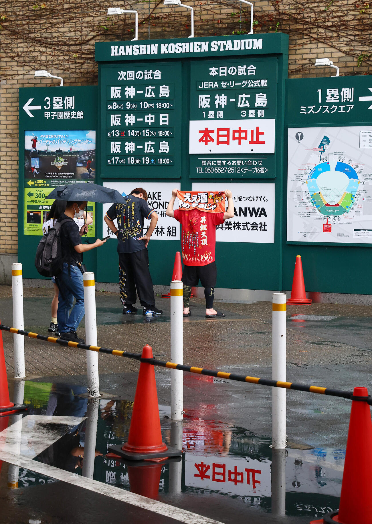 阪神対広島　中止看板のかかる掲示板を前に記念写真を撮るファン（撮影・加藤哉）