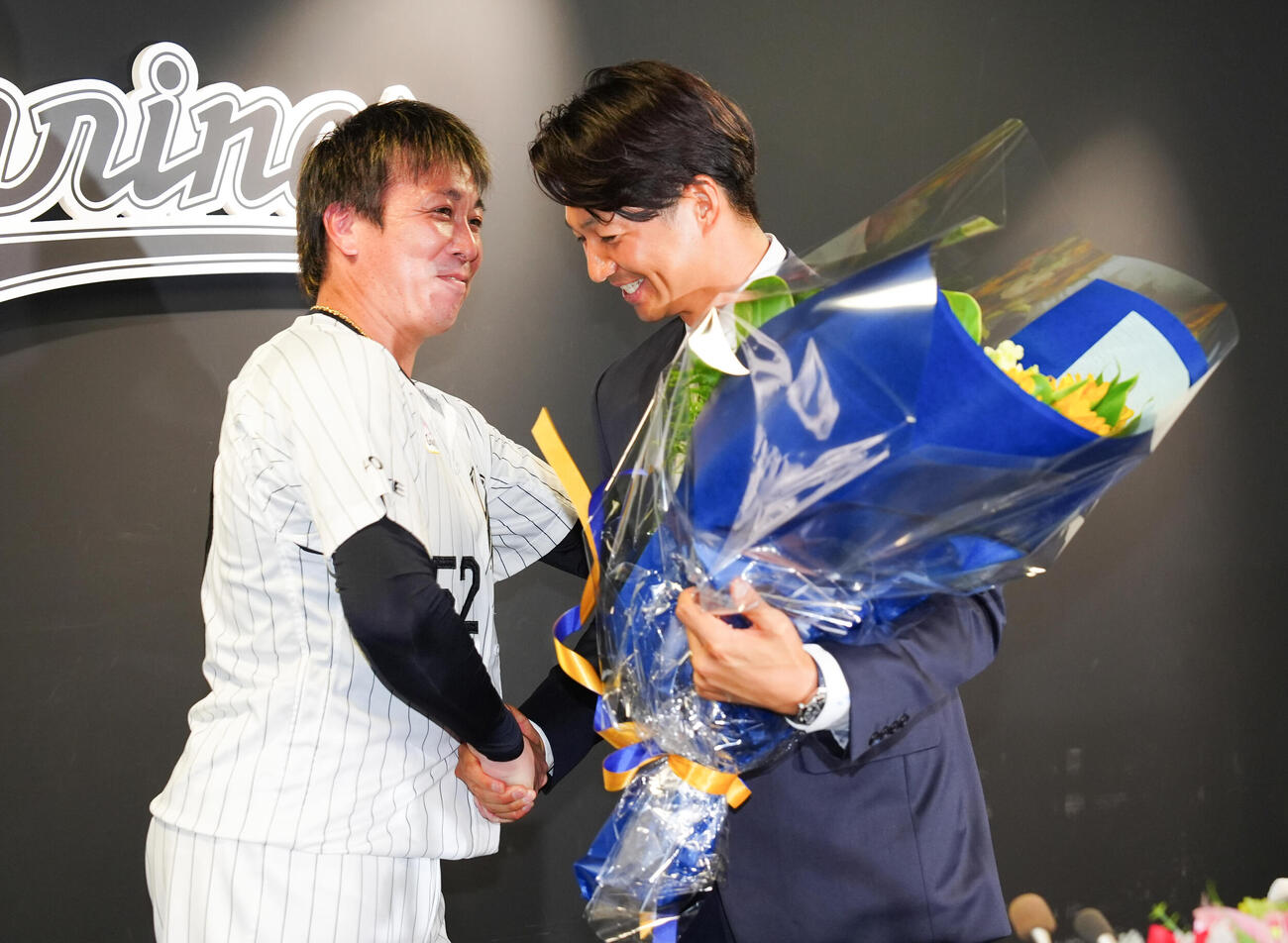 引退会見で益田直也（左）から花束を受け取るロッテ唐川侑己（撮影・鈴木みどり）