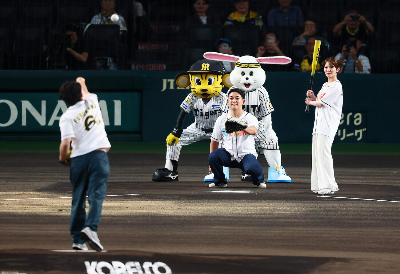 阪神対広島　古川昌希アナウンサーのファーストピッチを受けるABCの小櫃裕太郎アナウンサーと打席の鷲尾千尋アナウンサー（撮影・加藤哉）