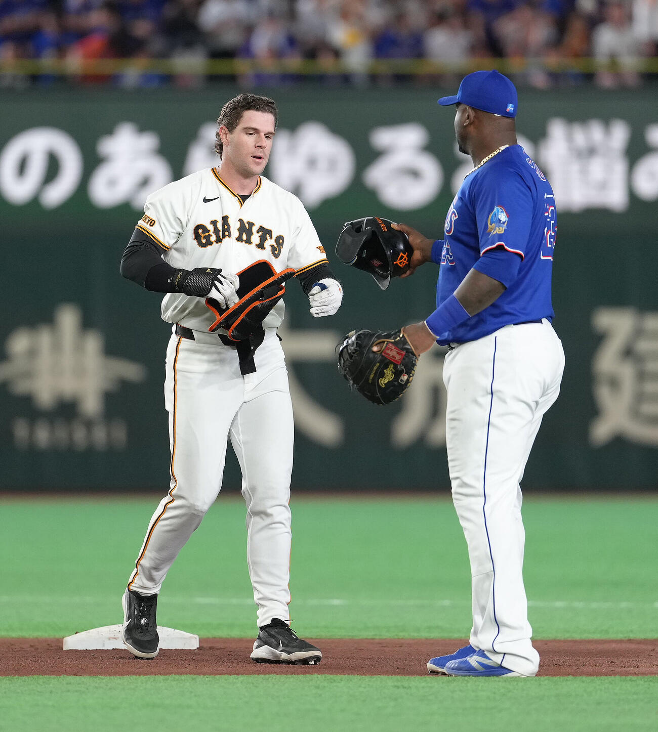 巨人対中日　4回裏巨人1死、トレイ・キャベッジ（左）は二塁打を放ち走塁中に落としたヘルメットを一塁手サノーに拾ってもらう（撮影・足立雅史）