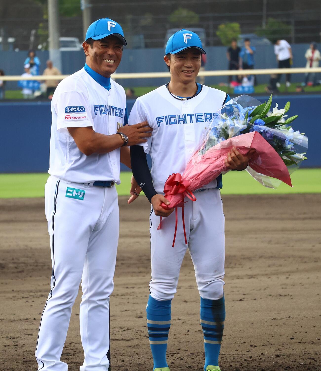 花束を贈呈する日本ハム稲葉篤紀2軍監督（左）と中島卓也（撮影・田島優大）
