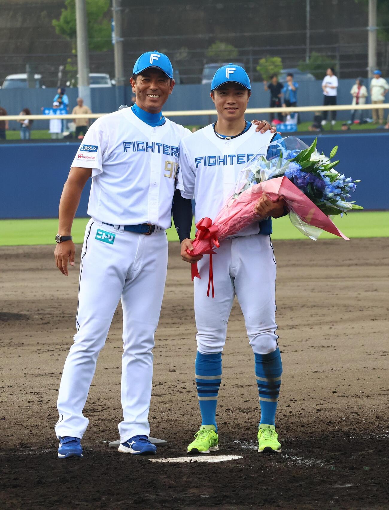 花束を贈呈する日本ハム稲葉篤紀2軍監督（左）と中島卓也（撮影・田島優大）
