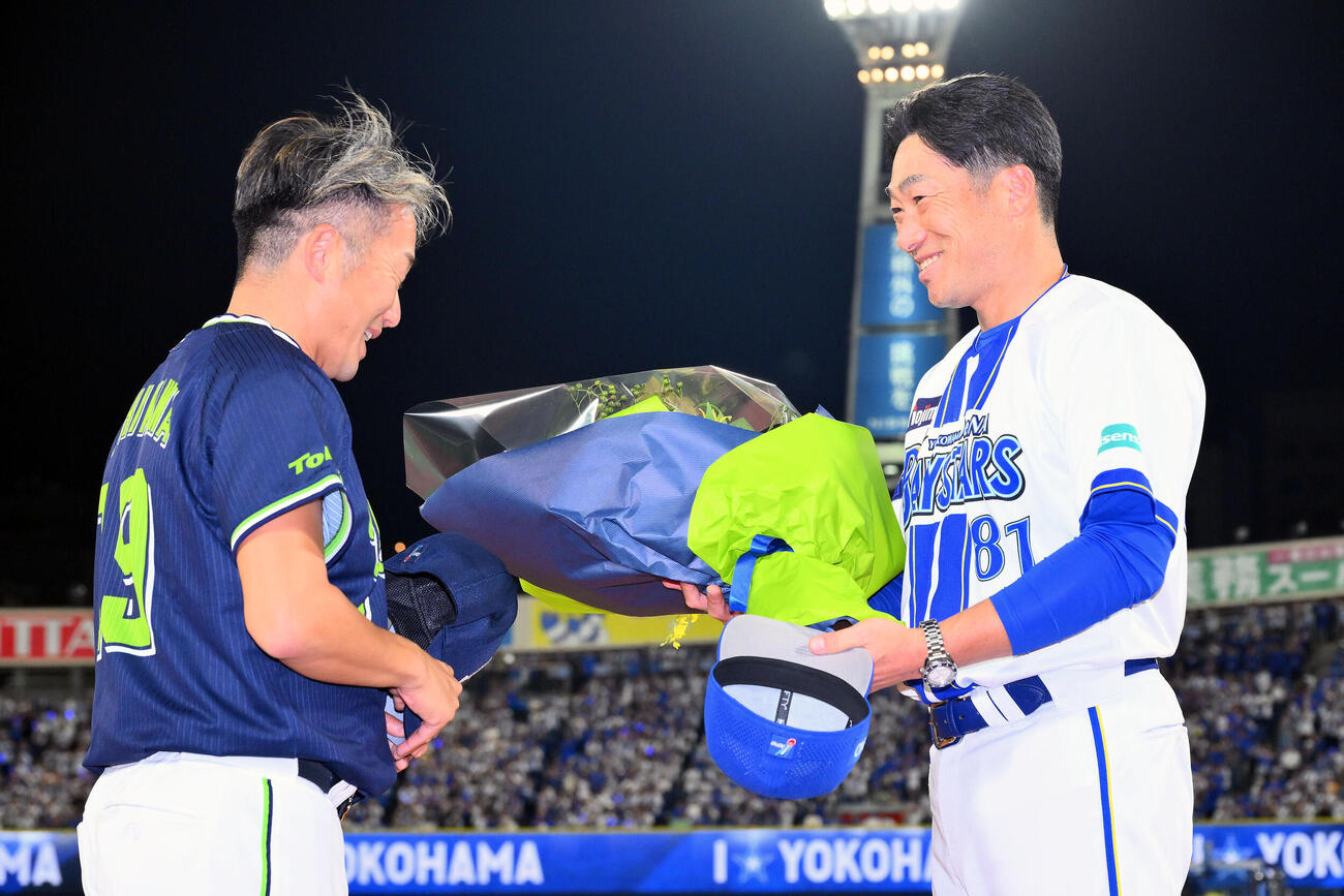 DeNA対ヤクルト　試合後、今季で引退するヤクルト石川雅規（左）はDeNA相川亮二監督から花束を受け取る（撮影・滝沢徹郎）