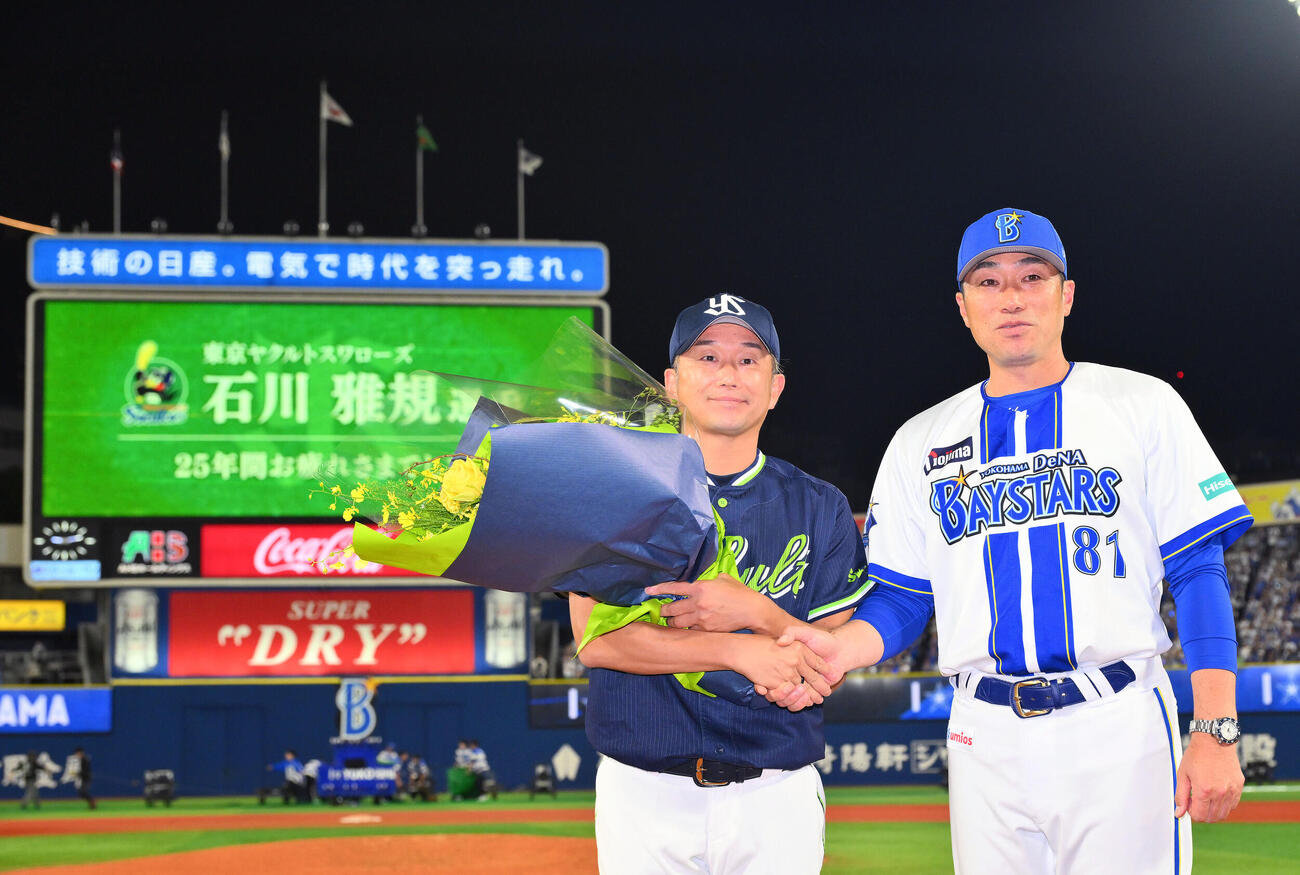 DeNA対ヤクルト　試合後、今季で引退するヤクルト石川雅規（左）はDeNA相川亮二監督から花束を受け取る（撮影・滝沢徹郎）