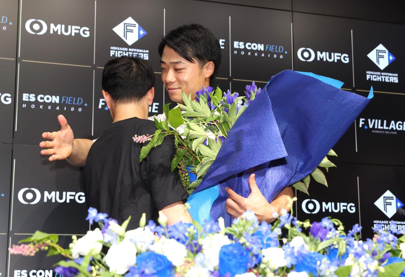 引退会見で奈良間大己から花束を受け取る日本ハム中島卓也（撮影・黒川智章）