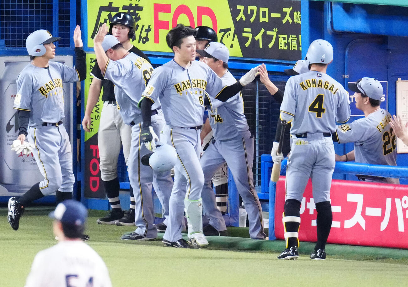 ヤクルト対阪神　11回表阪神無死一塁、2点本塁打を放ち、タッチを交わす高寺望夢（中央）。右端は藤川球児監督（撮影・江口和貴）