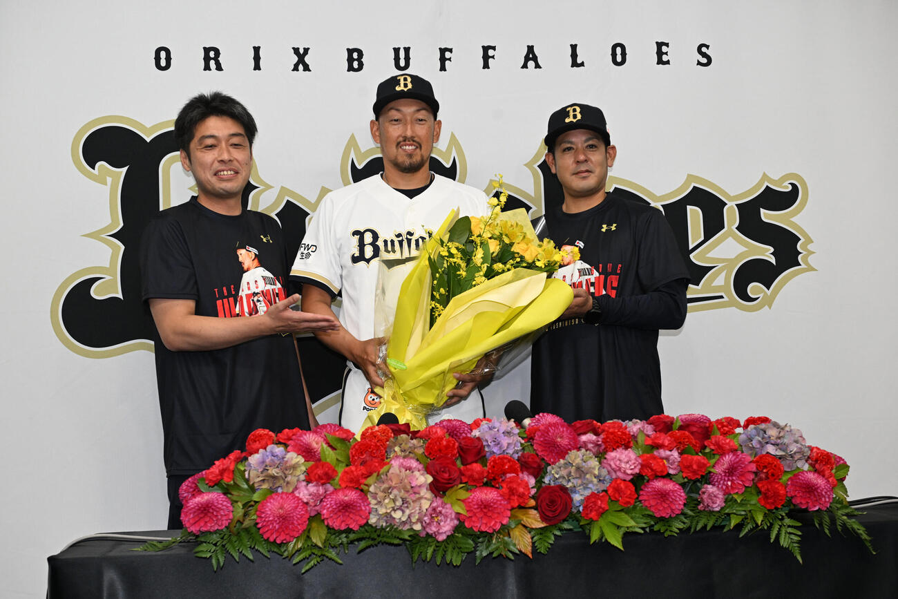 比嘉幹貴コーチ（右）から花束を贈られたオリックス平野佳寿は佐藤広報（左）とともに記念撮影する（撮影・和賀正仁）