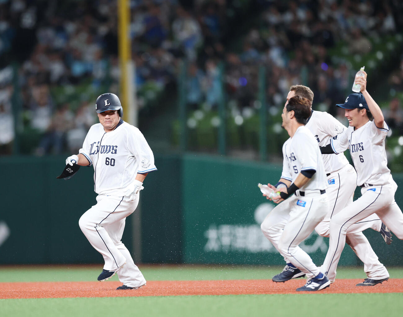 西武対ロッテ　サヨナラの適時打を放った中村剛也（左）は水をもったナインから全力で逃げる（撮影・増田悦実）