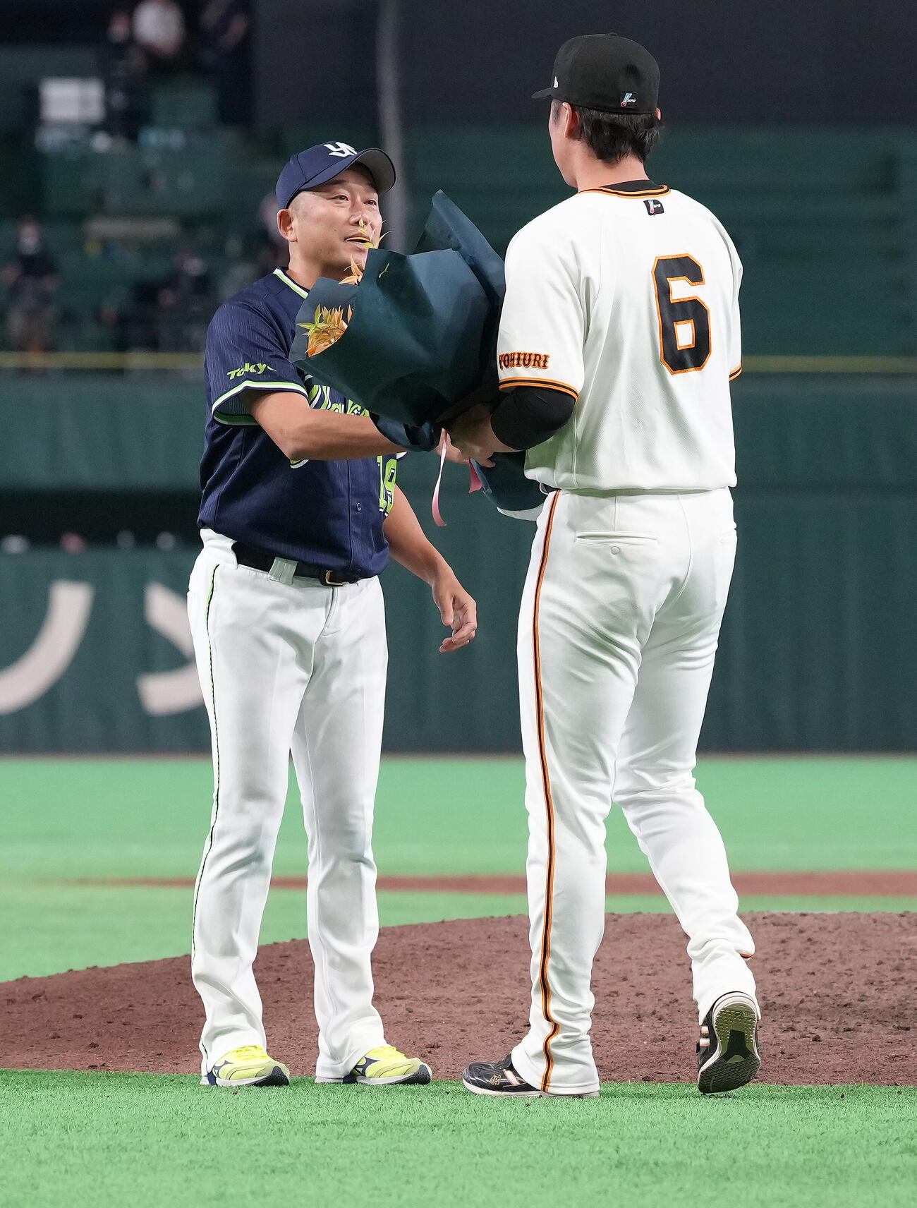 巨人対ヤクルト　今季で引退のヤクルト石川雅規（左）は巨人坂本勇人から花束を受け取る（撮影・足立雅史）