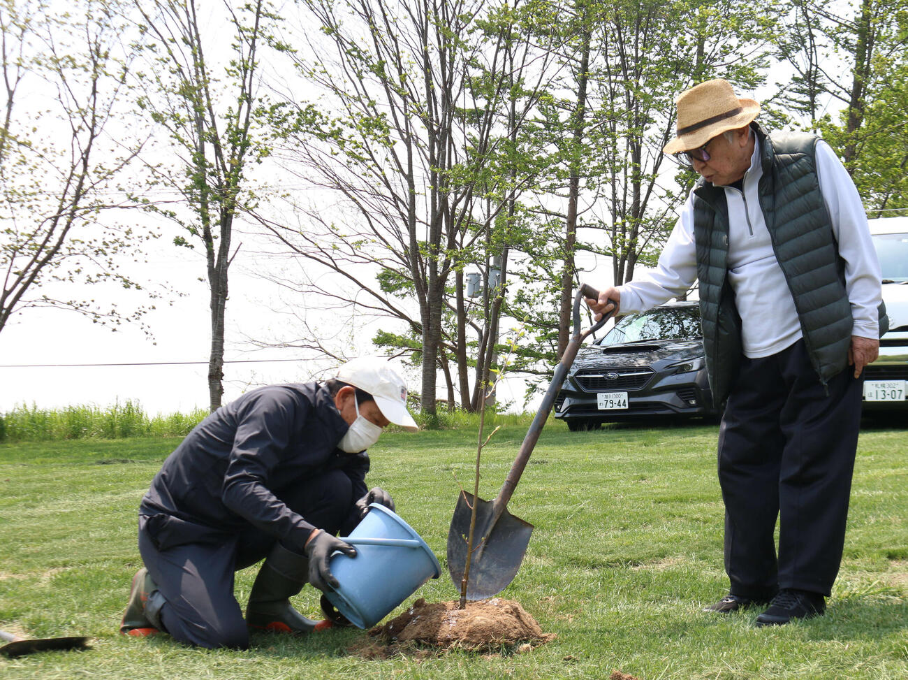 2022年5月、栗の樹の苗に水やりする日本ハム栗山プロフェッサー（左）を見守る倉本さん