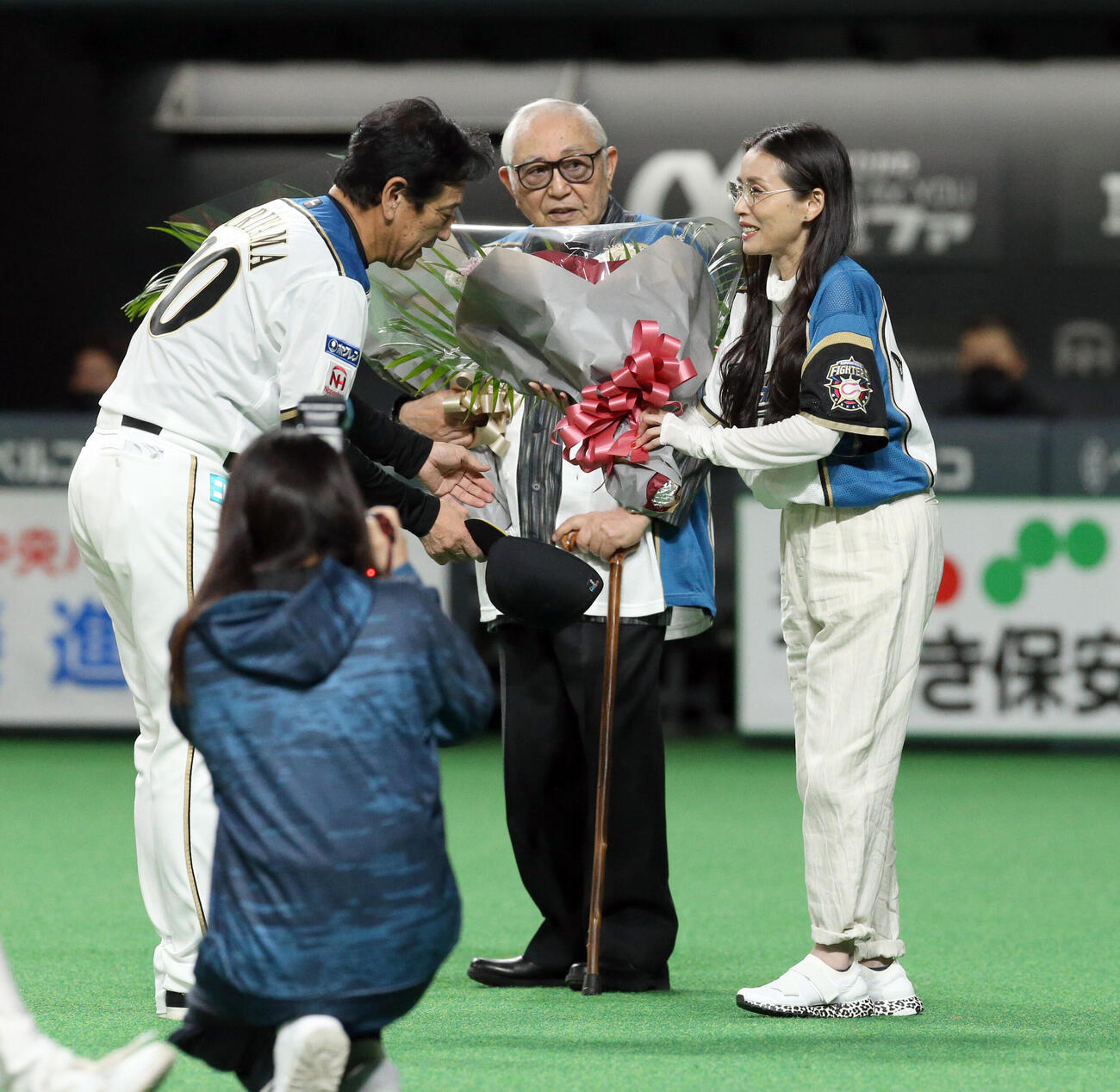 2021年10月、試合前、日本ハム栗山監督（左）から花束を贈呈される脚本家の倉本聰氏と中嶋朋子さん