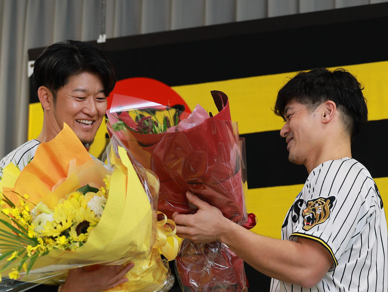 サプライズで登場した坂本誠志郎（右）から花束を受け取る岩貞祐太（撮影・上山淳一）
