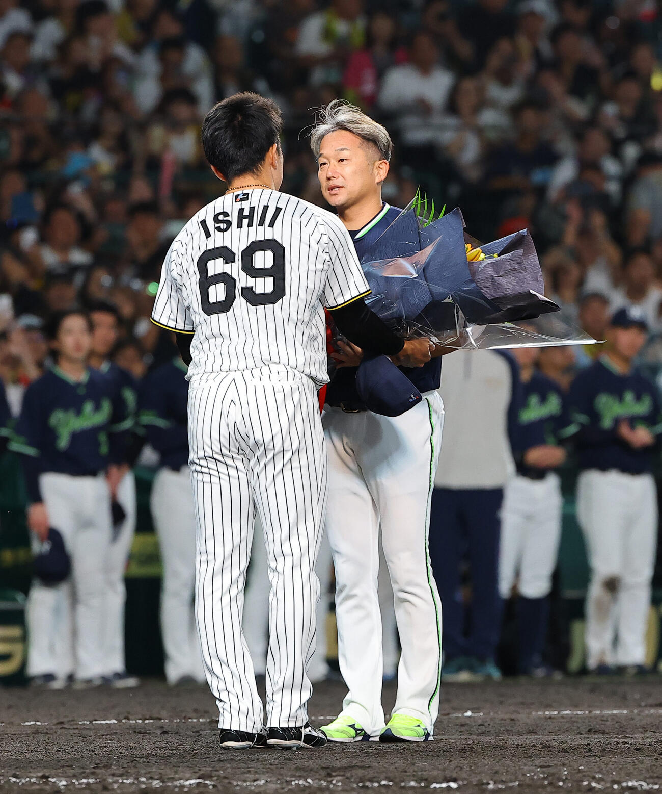 阪神対ヤクルト　引退するヤクルト石川雅規（右）は阪神石井大智から花束を受け取る（撮影・上田博志）