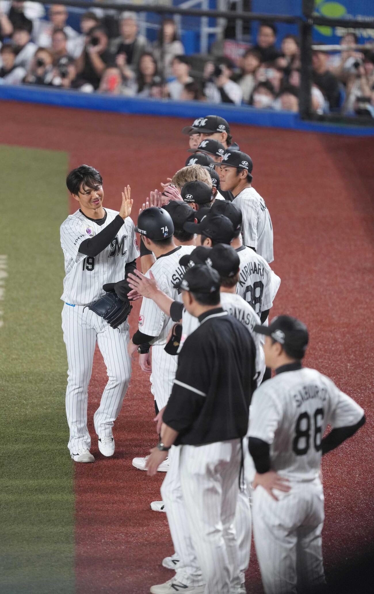 ロッテ対ソフトバンク　1回表ソフトバンク1死、引退登板を終えた唐川侑己（左）はベンチ前に整列したナインの祝福を受ける（撮影・小沢裕）