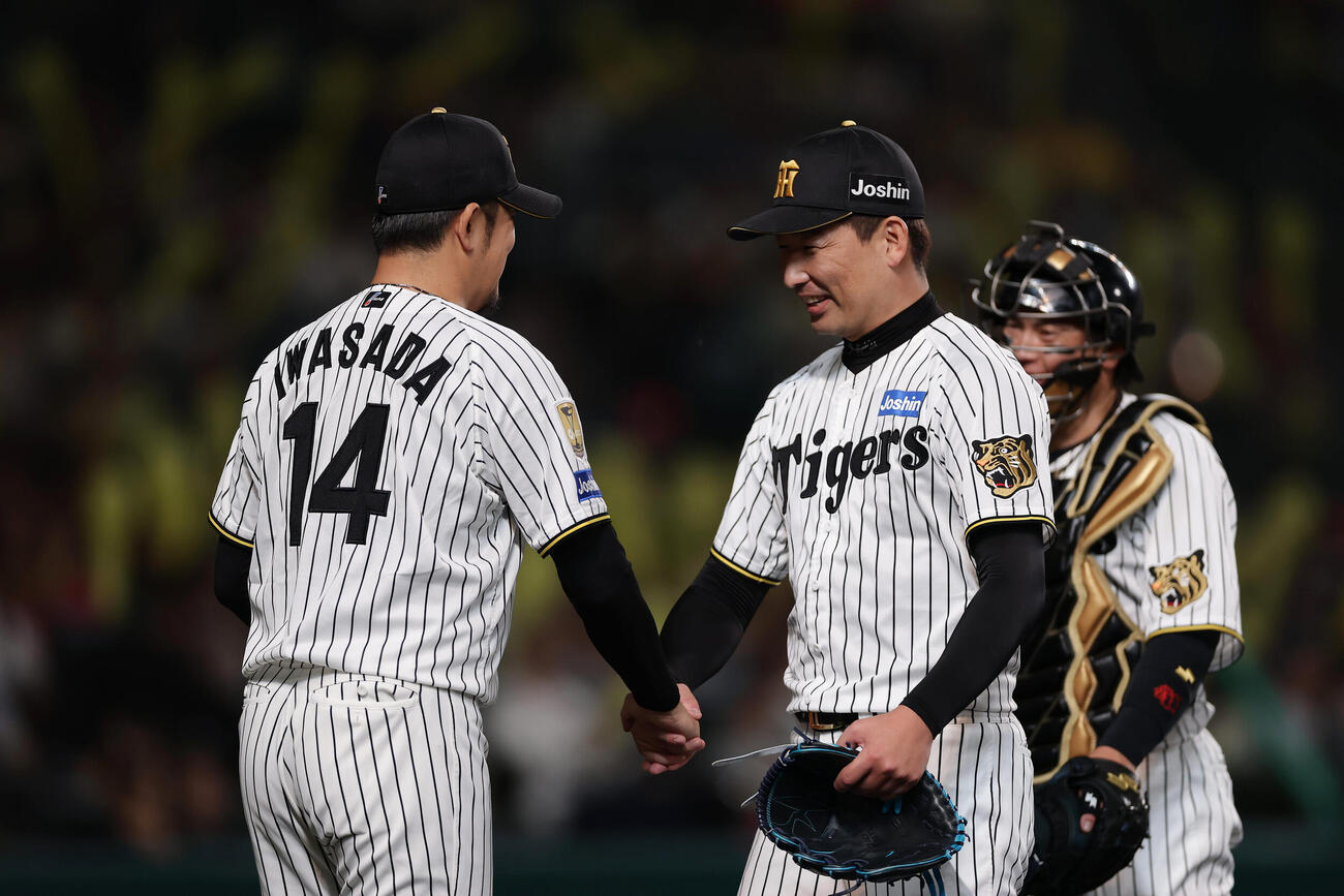 阪神対広島　7回表、登板を終えた岩崎優（右）と握手を交わす阪神岩貞祐太。後方は梅野隆太郎（撮影・前田充）