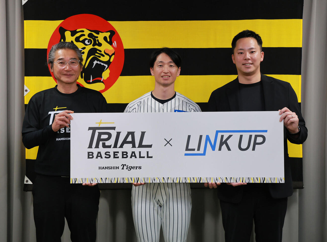 フォトセッションで笑顔を見せる、左から阪神嶌村聡専務取締役、阪神近本光司、LINK UPの石井僚介代表理事（撮影・上山淳一）