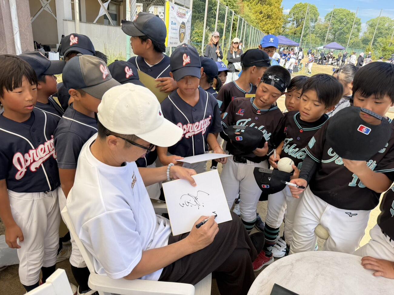 第2回今岡真訪杯なにわキッズソフトボール大会に参加した少年少女は今岡氏にサインを求める