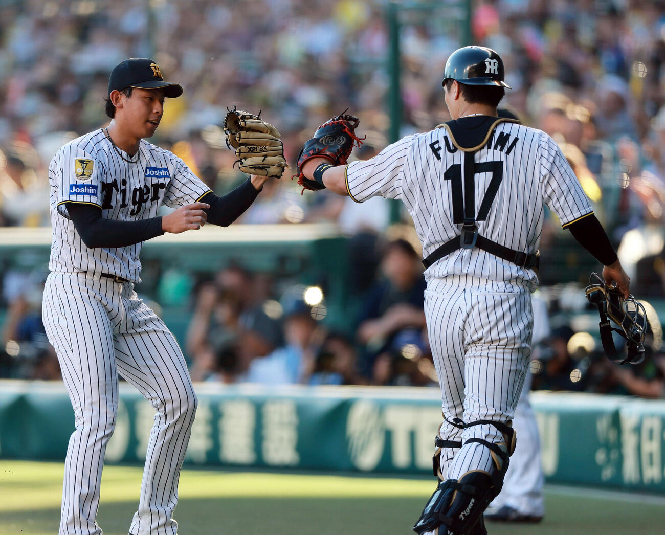 阪神対DeNA 6回表DeNA2死一、三塁、神宮僚介（左）は成瀬脩人を空振り三振に仕留めベンチ前で捕手伏見寅威とタッチをかわす（撮影・上山淳一）