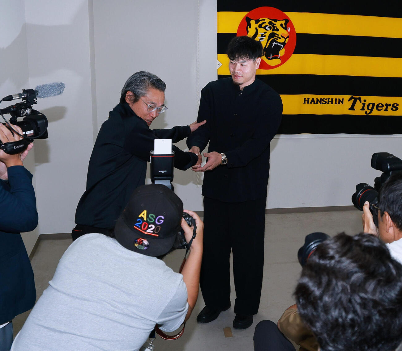 代表インタビューを終え阪神嶌村聡球団本部長（左）から激励を受ける佐藤輝明（撮影・上山淳一）