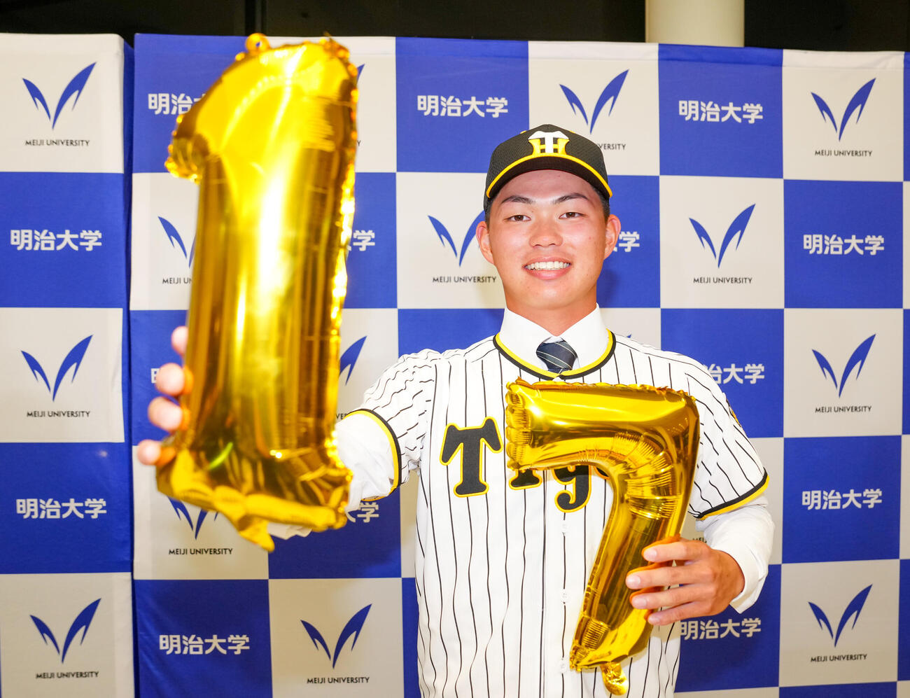 明大「17」年連続ドラフト指名、阪神「1」位指名、名前の七斗の「7」で写真に納まる明大・榊原七斗（撮影・江口和貴）
