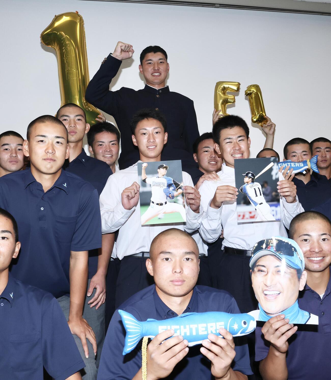 チームメートから騎馬で祝福を受けながら写真に納まる日本ハムから1位指名を受けた山梨学院・菰田陽生（上）（撮影・河田真司）