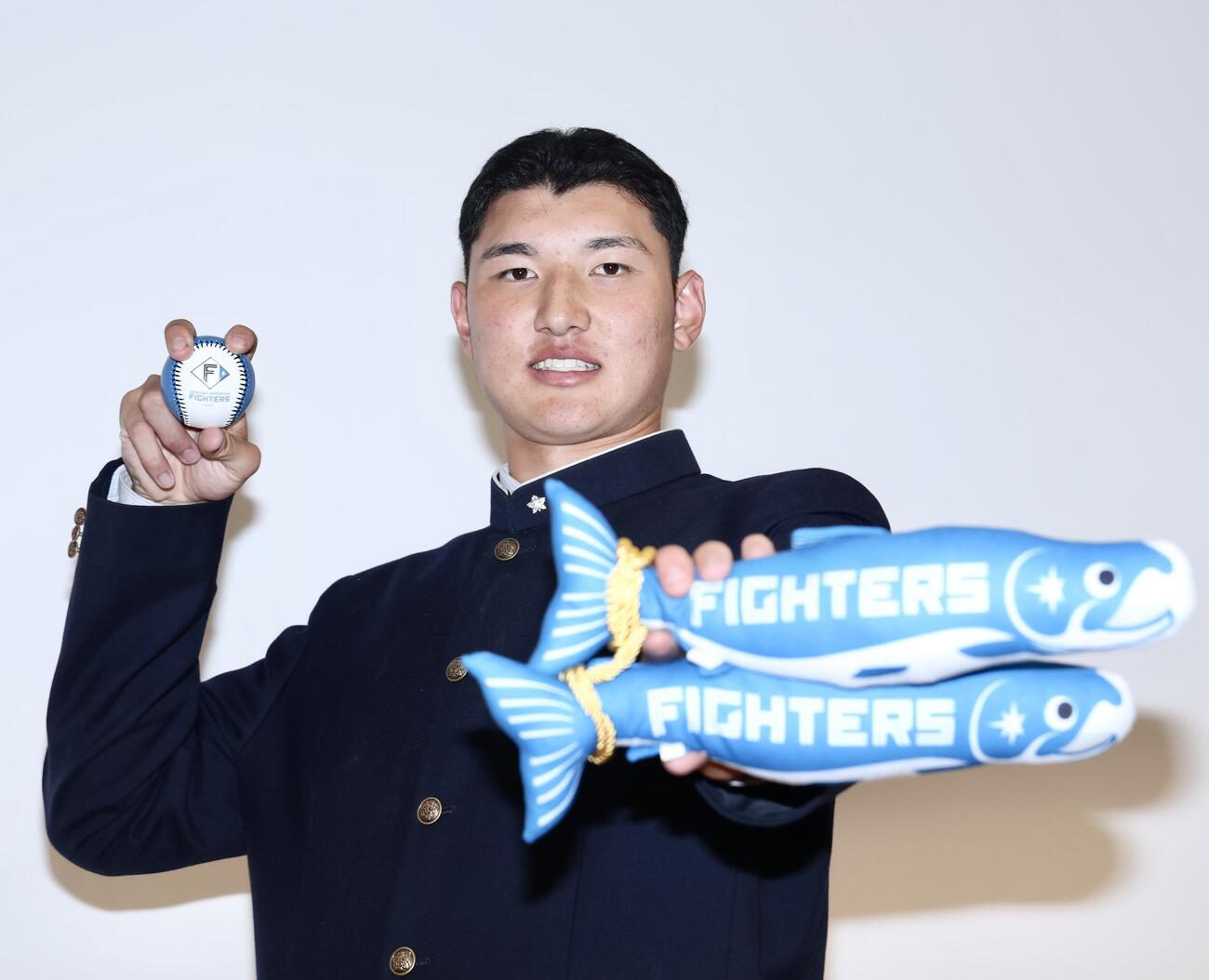 グッズを手に写真に納まる日本ハムから1位指名を受けた山梨学院・菰田陽生（撮影・河田真司）